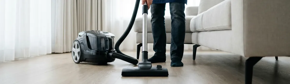 Professional house cleaner vacuuming a living room floor with a canister vacuum cleaner, Columbia, SC.